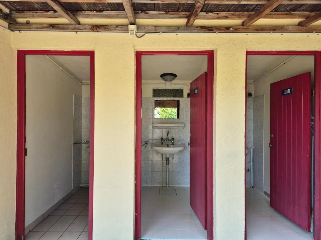 La salle de bains est pourvue de deux portes rouges et d'un lavabo. dans l'établissement La Bedure, à Luzy 15 autres photos