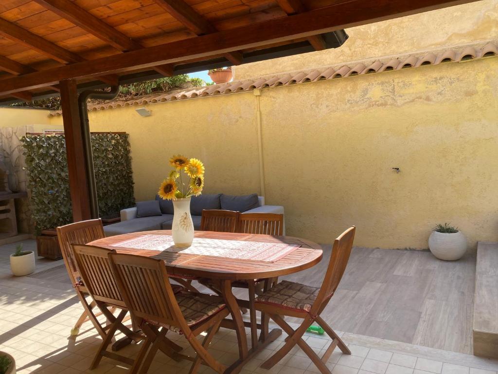 une table et des chaises avec un vase de fleurs sur la terrasse dans l'établissement Villa mari&amuri, à Noto