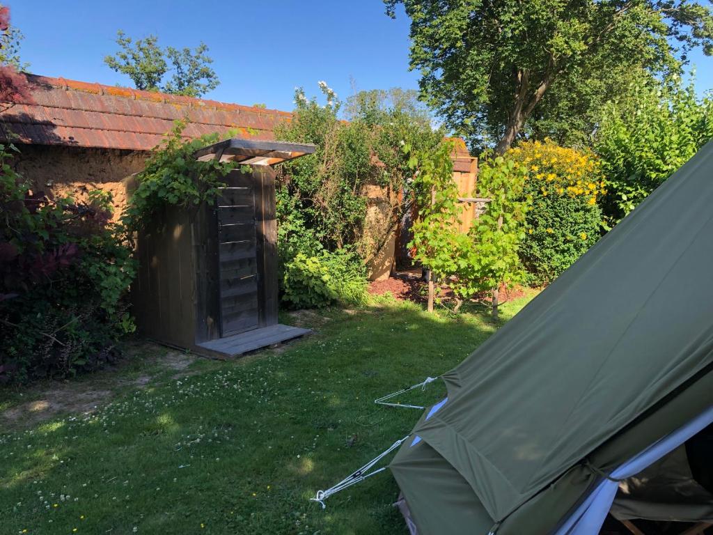 une tente installée dans l'herbe à côté d'un jardin dans l'établissement Le Clos des Reines, à Conteville