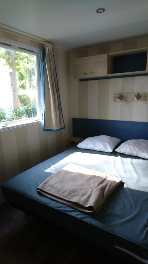 - un lit avec couverture dans une chambre avec fenêtre dans l'établissement 45mn de Paris-Mobilhome pour familles et travail-B57, à Saint-Chéron