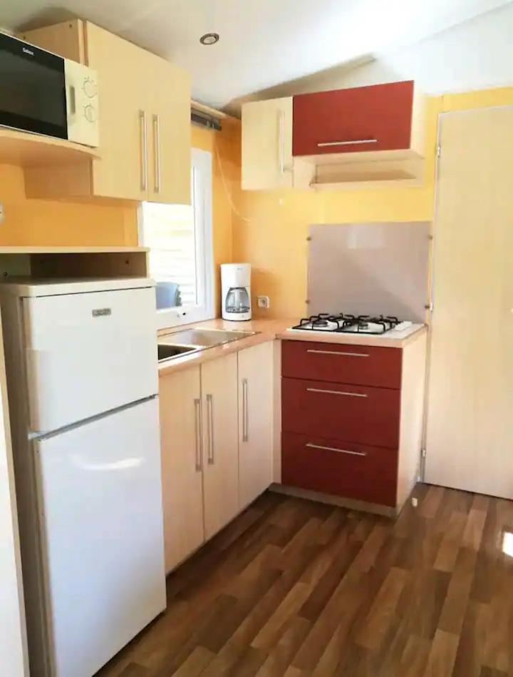 Il comprend une petite cuisine avec des appareils électroménagers blancs et du parquet. dans l'établissement 45mn de Paris Sympathique logement trois chambres - A76, à Saint-Chéron