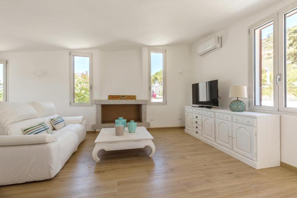 un salon blanc avec un canapé blanc et une télévision dans l'établissement Villa Angelina con piscina e giardino privato a pochi passi dalla Spiaggia di Campus, à Villasimius