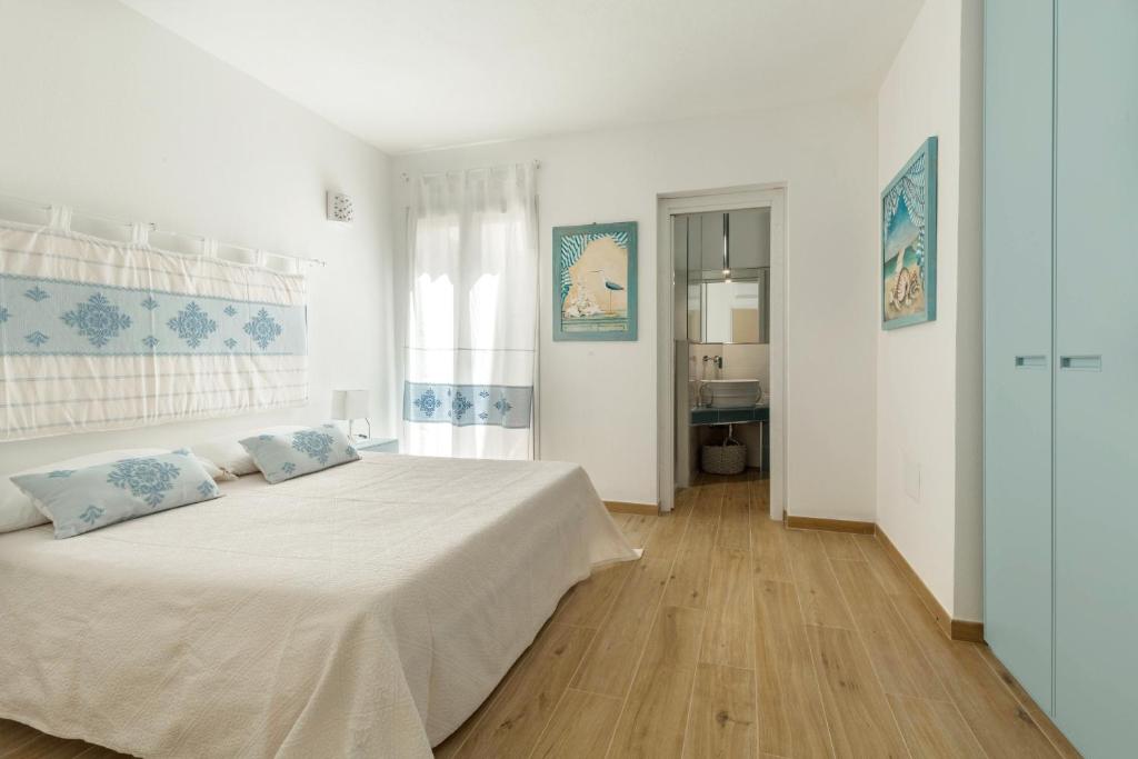 une chambre blanche avec un grand lit avec des oreillers bleus dans l'établissement Villa Angelina con piscina e giardino privato a pochi passi dalla Spiaggia di Campus, à Villasimius 27 autres photos