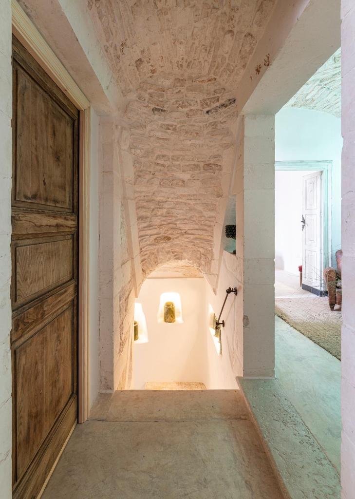 un couloir vide avec une porte et un mur en pierre dans l'établissement Torretta Martina, à Martina Franca