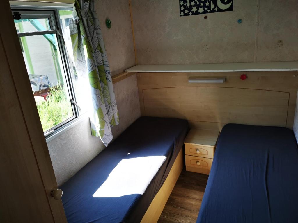 une petite pièce avec un lit et une fenêtre dans l'établissement Bungalow camping 3 étoiles, à Chazelles-sur-Lyon