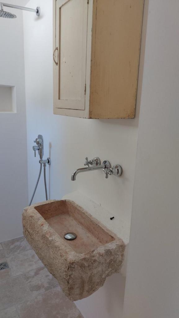 une salle de bain avec un lavabo en pierre et un miroir dans l'établissement Trullo Terra Bianca, à Ostuni 39 autres photos