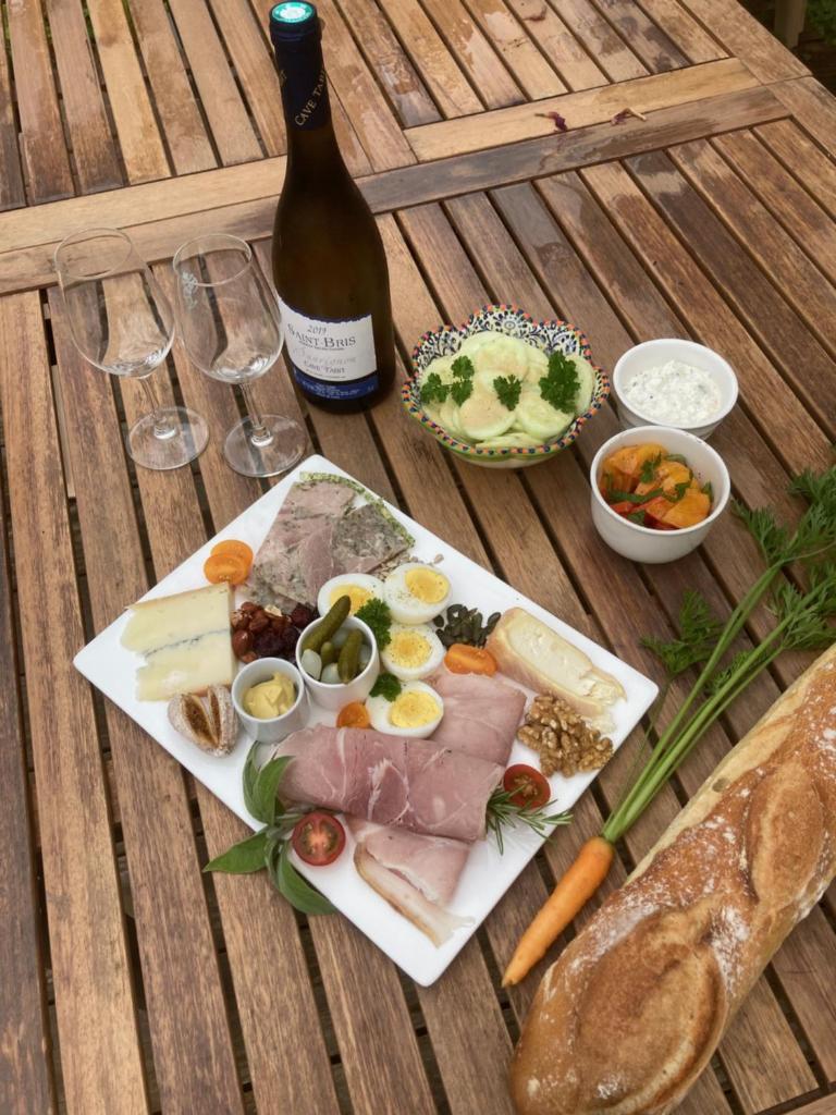 - une table avec une assiette de nourriture et une bouteille de vin dans l'établissement Le jardin secret, à Semur-en-Auxois