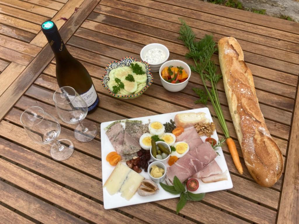 - une table avec une assiette de nourriture et une bouteille de vin dans l'établissement Le jardin secret, à Semur-en-Auxois