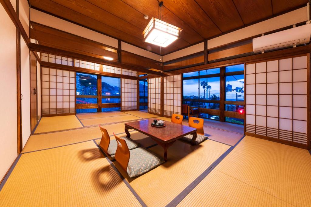 une salle à manger avec une table, des chaises et des fenêtres dans l'établissement Jyokiya, à Unzen