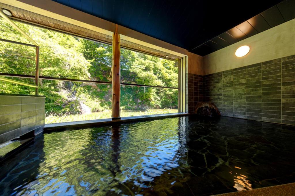 Cette chambre dispose d'une piscine d'eau et d'une grande fenêtre. dans l'établissement Namari Onsen Kokoro No Toki Jusangatsu, à Hanamaki
