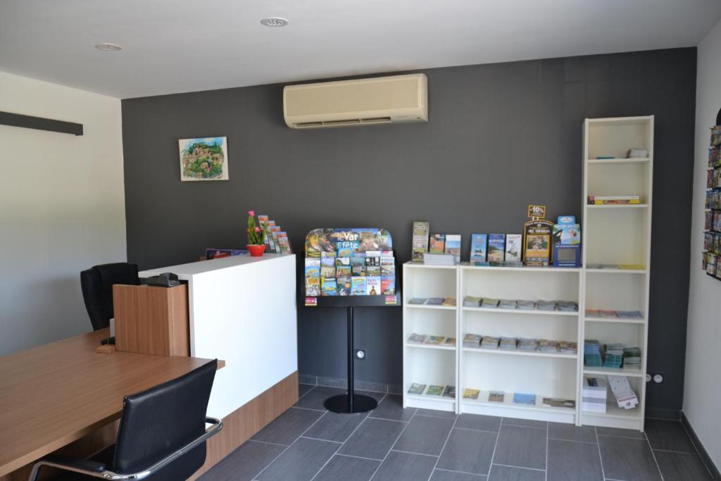 une salle d'attente avec un comptoir, une table et des étagères dans l'établissement Camping Parc Valrose, à La Londe-les-Maures