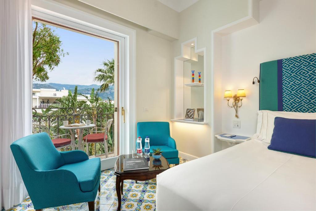 - une chambre avec un lit, deux chaises et une grande fenêtre dans l'établissement Grand Hotel Ambasciatori, à Sorrente
