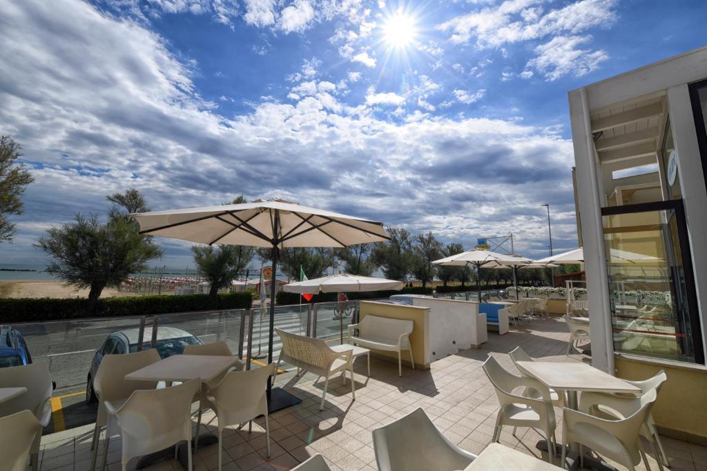 un patio avec tables, chaises et un parasol dans l'établissement Hotel Ancore, à Senigallia 28 autres photos