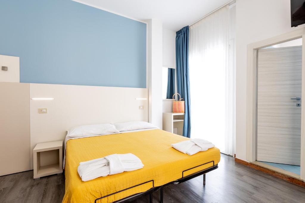 - une chambre avec un lit jaune et des serviettes dans l'établissement Hotel Kim, à Rimini
