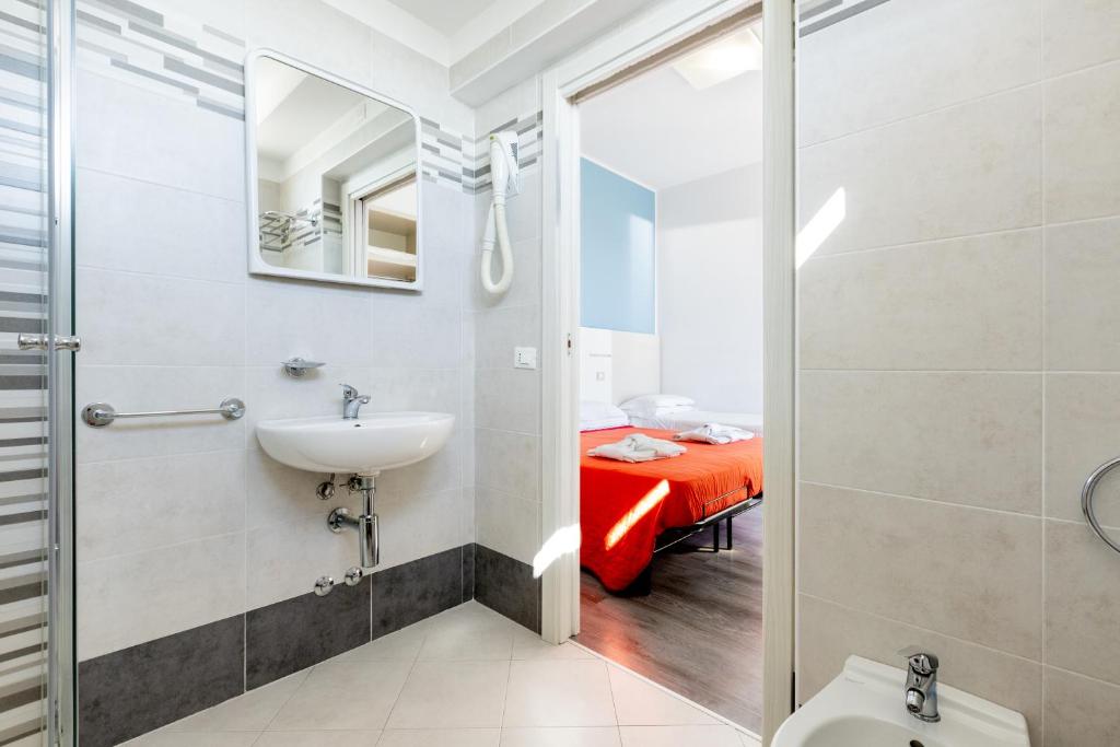 une salle de bain avec un lavabo et des toilettes et un lit dans l'établissement Hotel Kim, à Rimini