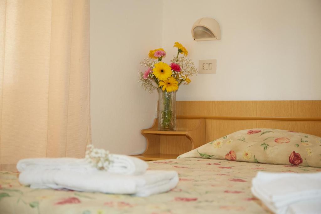 un vase de fleurs et de serviettes sur un lit dans l'établissement Hotel ITALIACERVIA, à Cervia