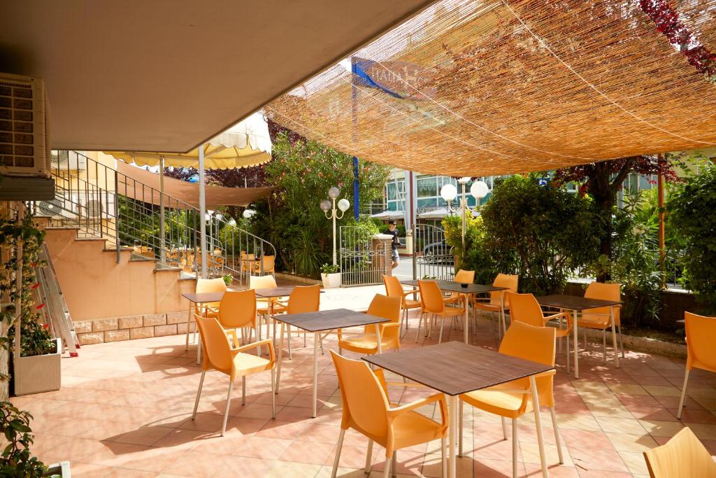 un patio extérieur avec des tables, des chaises, des tables et des chaises dans l'établissement Hotel ITALIACERVIA, à Cervia