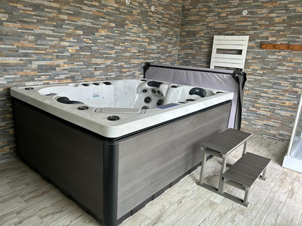 - un bain à remous dans une pièce avec une chaise dans l'établissement le domaine du bez gite de la grise piscine sauna hammam spa, à Saint-Laurent-dʼOlt