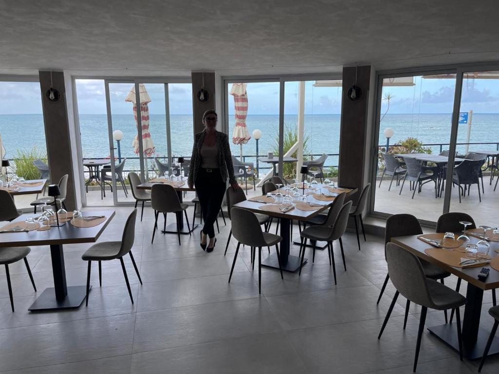 Un homme se promène dans un restaurant avec des tables et des chaises. dans l'établissement Hotel Ristorante Mareblu, à Amantea