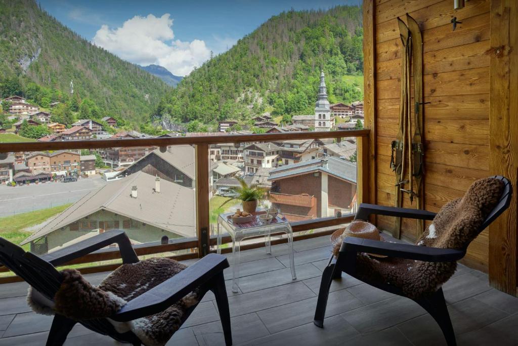 - deux chaises sur un balcon avec vue sur la ville dans l'établissement Le Grand Capricia - OVO Network, à La Clusaz