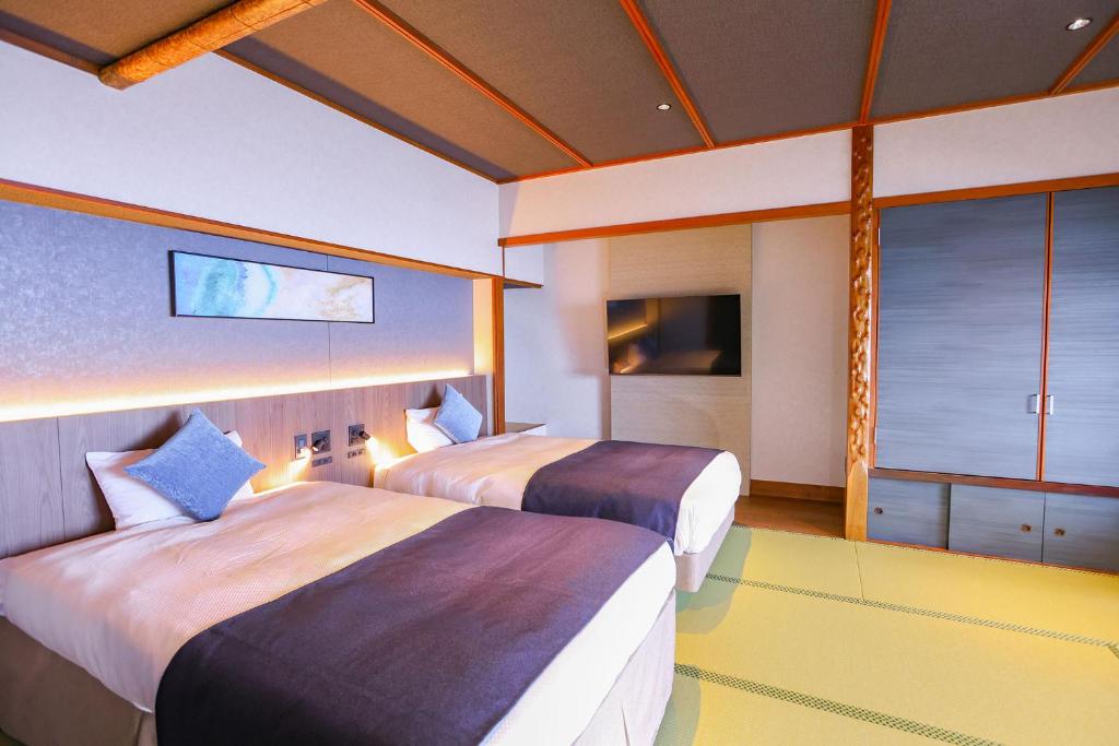 une chambre d'hôtel avec deux lits et une télévision dans l'établissement Ooedo Onsen Monogatari Premium Atami, à Atami
