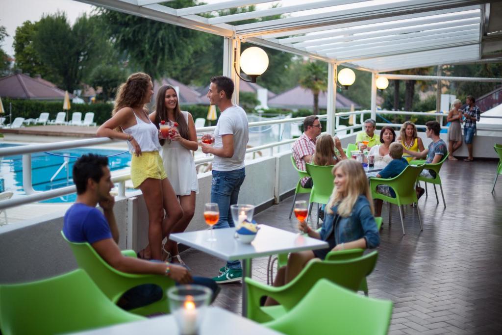 un groupe de personnes debout sur le pont d'un restaurant dans l'établissement Aparthotel Albatros, à Lignano Sabbiadoro