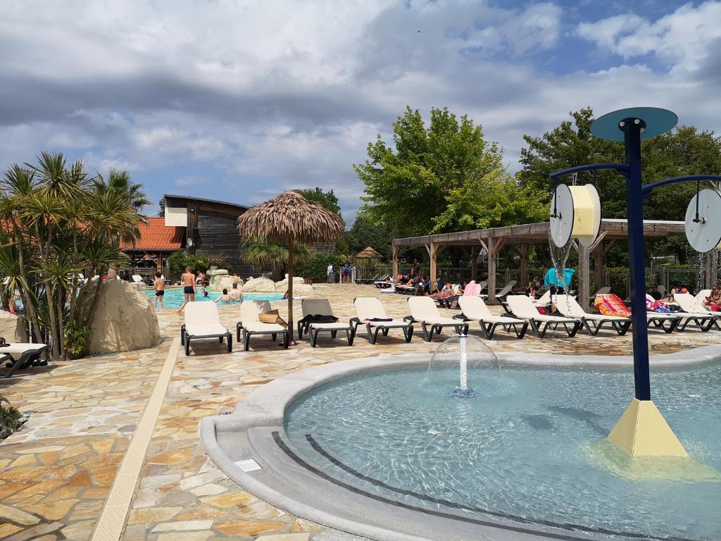 une fontaine au milieu d'une piscine avec des chaises dans l'établissement Biscarrosse MOBIL HOME Privilège XXL 6P Climatisé 40 m2, à Biscarrosse