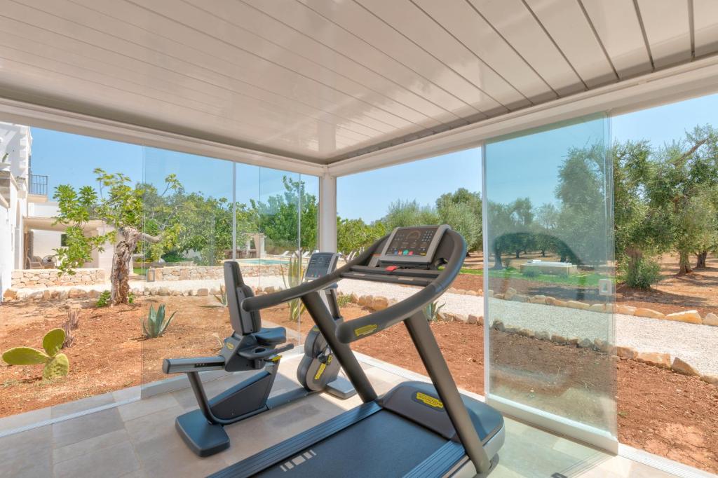 - une salle de sport avec un tapis de course devant une grande fenêtre dans l'établissement Masseria Artemisia Ostuni, à Ostuni