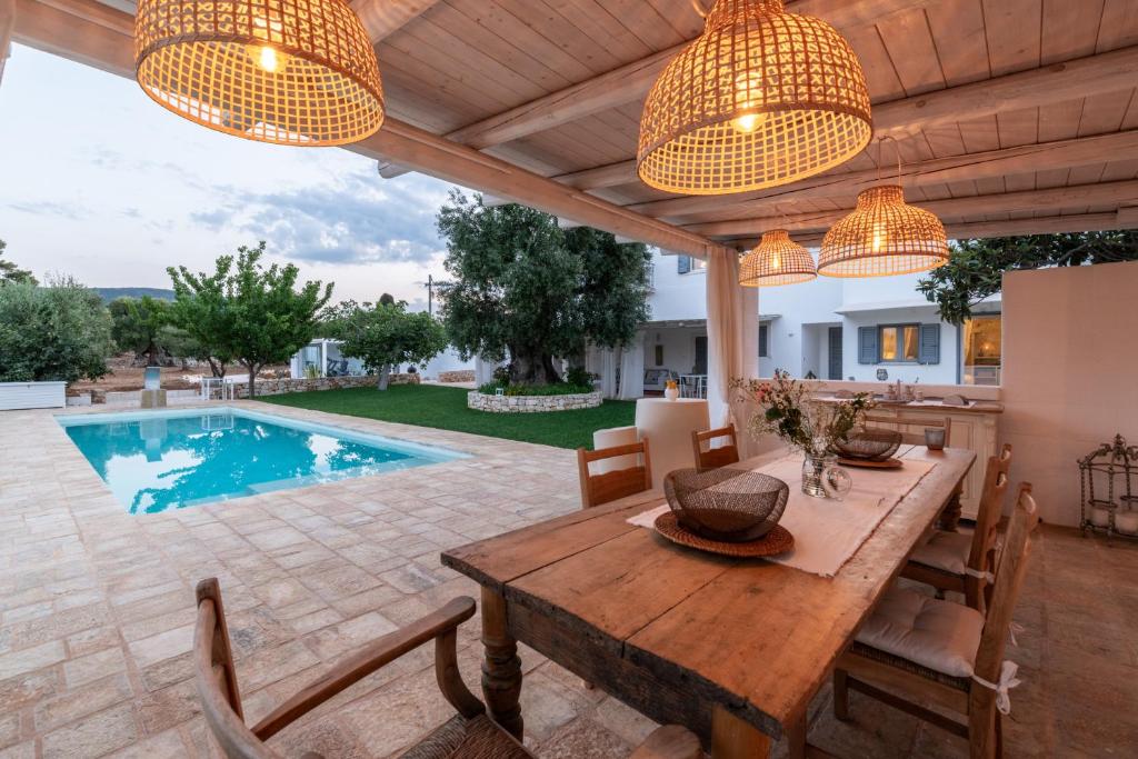 une terrasse avec une table en bois et une piscine dans l'établissement Masseria Artemisia Ostuni, à Ostuni