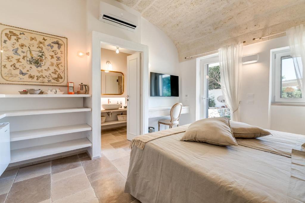 une chambre avec un grand lit et un bureau dans l'établissement Masseria Artemisia Ostuni, à Ostuni