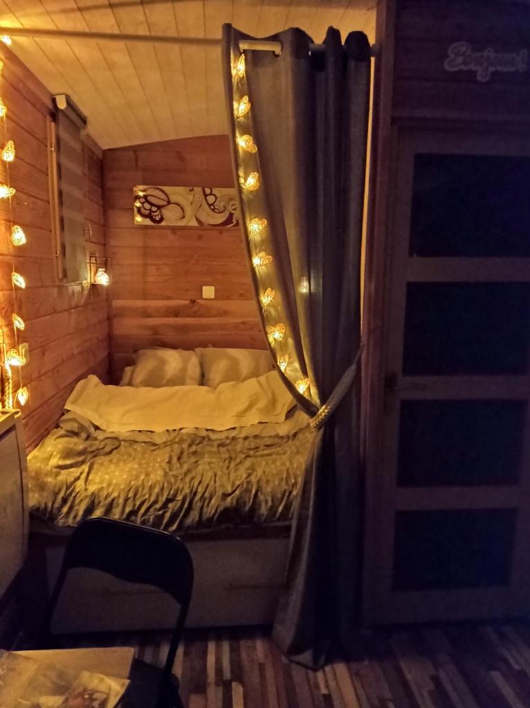 - une petite chambre avec un lit et un rideau dans l'établissement Roulotte de la Ferme Les Chenevières, à Villers-devant-Mouzon
