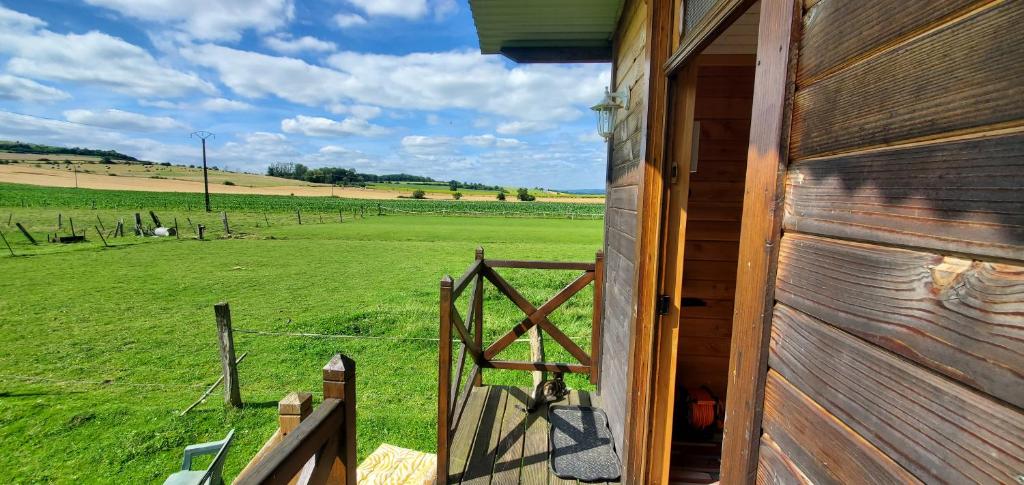 une porte menant à une grange avec vue sur un champ dans l'établissement Roulotte de la Ferme Les Chenevières, à Villers-devant-Mouzon