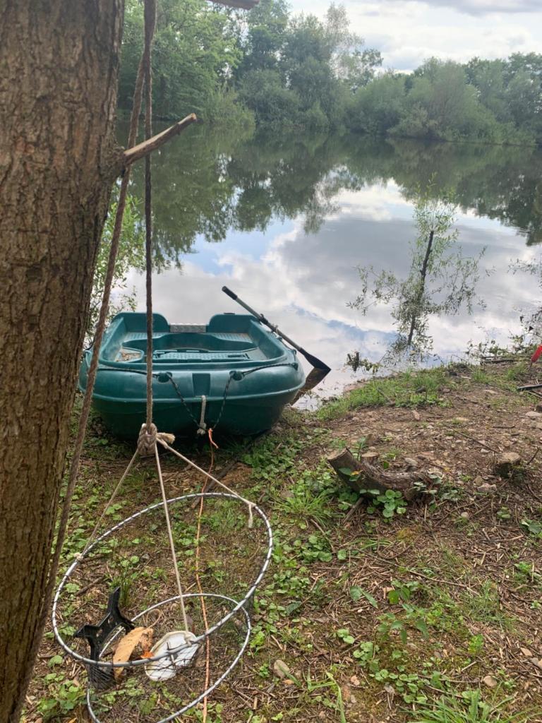 un bateau vert assis sur le côté d'un lac dans l'établissement Nuit en van au bord étang privé, à Saint-Sauveur 1 autre photo