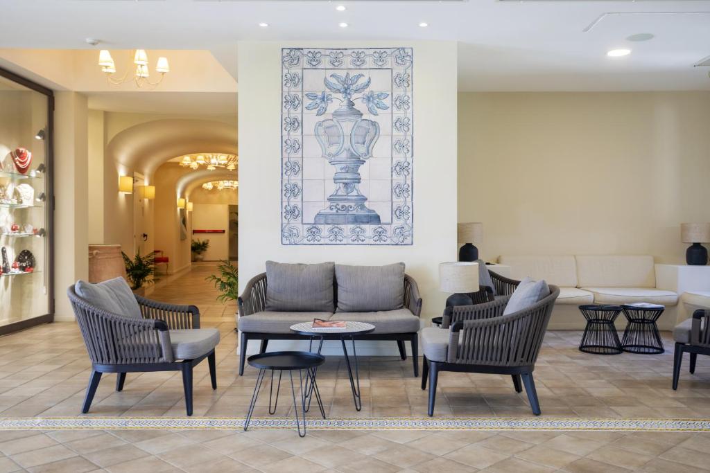 - un hall avec des chaises, une table et une photo sur le mur dans l'établissement Mangia's Selinunte Resort, à Marinella di Selinunte