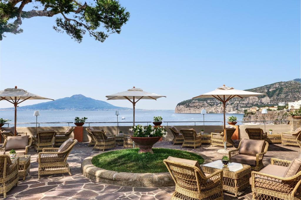 une terrasse avec des chaises, des tables et des parasols dans l'établissement Grand Hotel Ambasciatori, à Sorrente