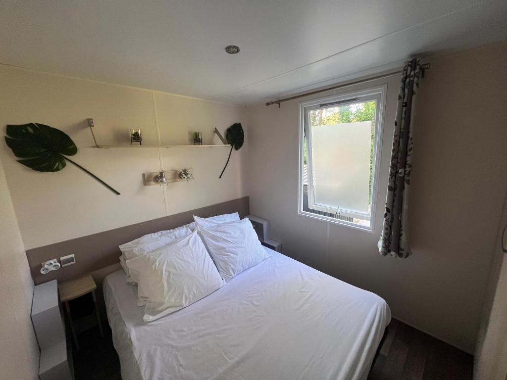une chambre avec un lit avec des draps blancs et une fenêtre dans l'établissement Ivry calme détente piscine sport famille by Vayny, à Ivry-la-Bataille