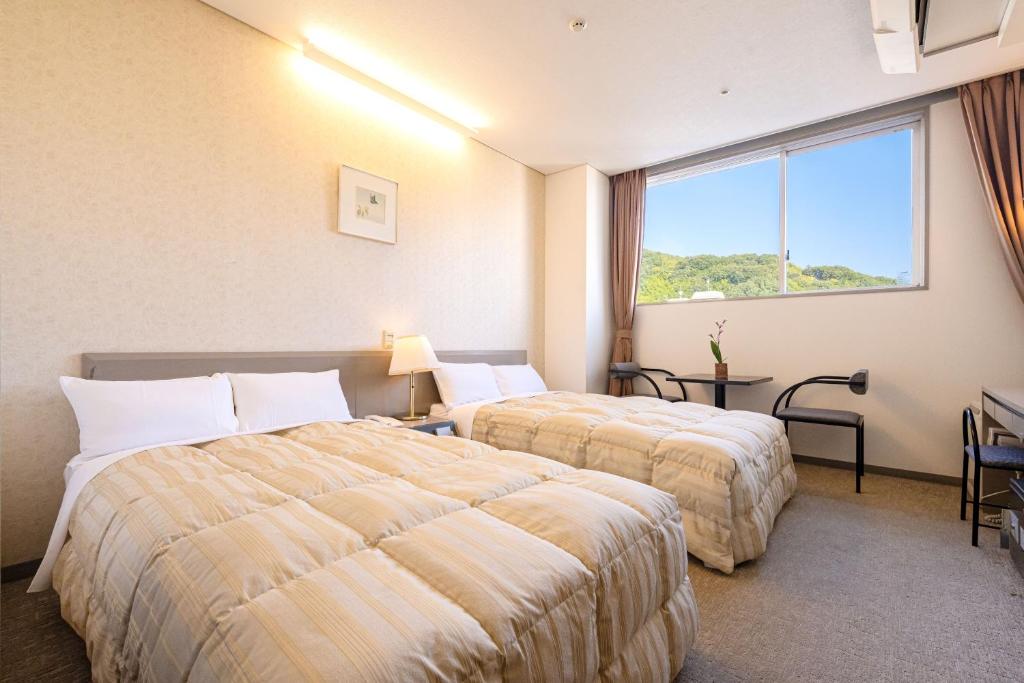 une chambre d'hôtel avec deux lits et une fenêtre dans l'établissement Dogo Kan, à Matsuyama