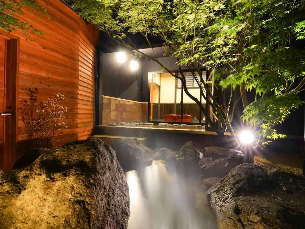 une maison avec une cascade dans une pièce avec des lumières dans l'établissement 匠晴の宿 心庵, à Beppu