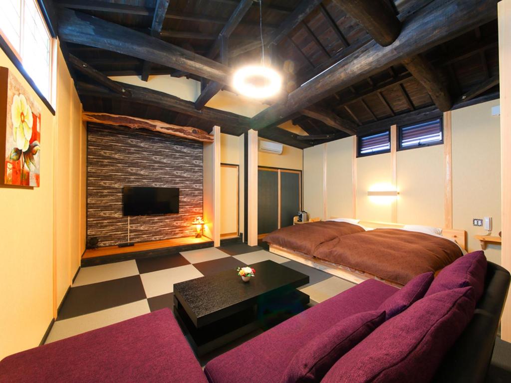 une pièce avec un canapé, un lit et une cheminée dans l'établissement 匠晴の宿 心庵, à Beppu