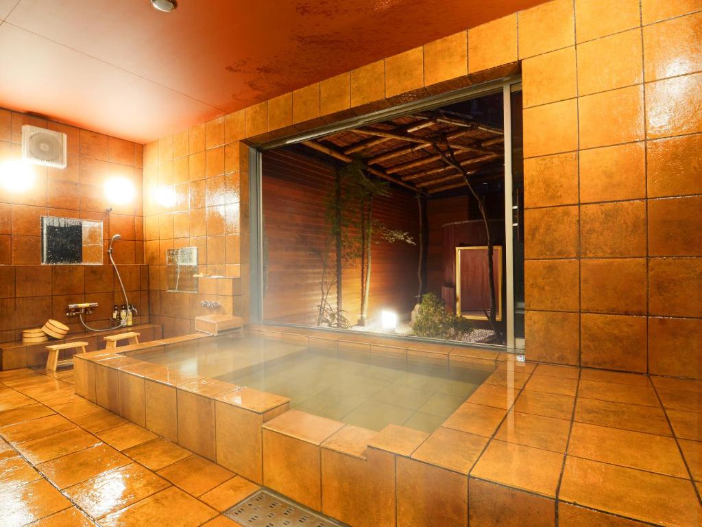 une grande baignoire dans une pièce avec une grande fenêtre dans l'établissement 匠晴の宿 心庵, à Beppu