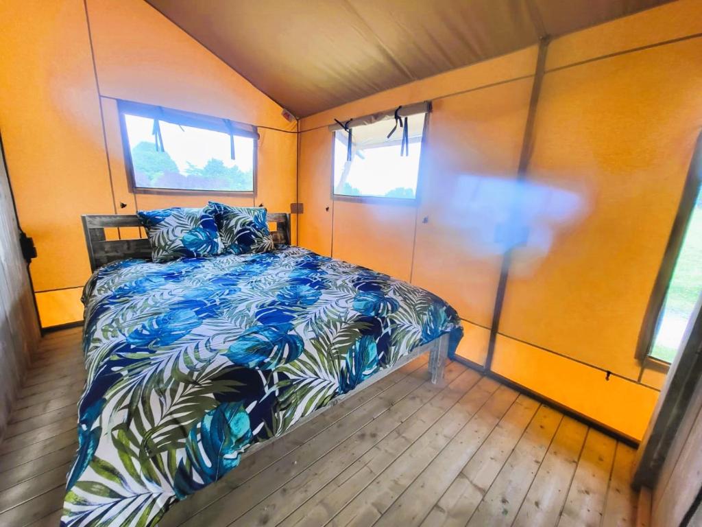 une chambre avec un lit dans une pièce avec des fenêtres dans l'établissement Les lodges de Baca, à Le Voide