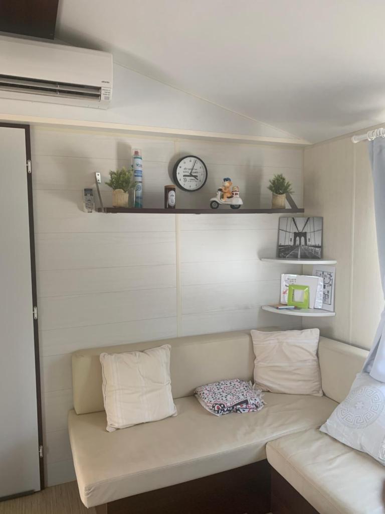 - un canapé blanc dans une chambre avec une horloge murale dans l'établissement Flo mobil home camping Poney trois étoiles route de Moustiers Ste Croix, à Sainte-Croix-de-Verdon