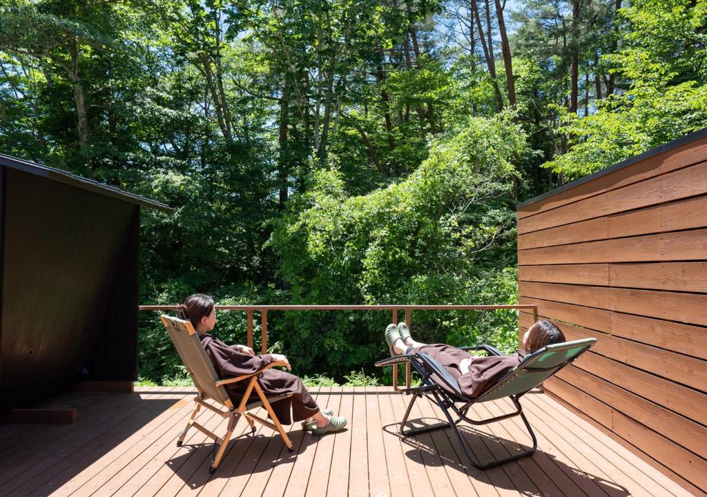 deux personnes assises dans des chaises à bascule sur une terrasse dans l'établissement Morino Hotel, à Kiso