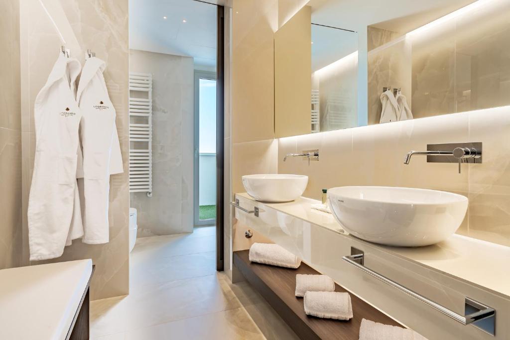 une salle de bain avec deux lavabos et un grand miroir dans l'établissement Litoraneo Suite Hotel, à Rimini