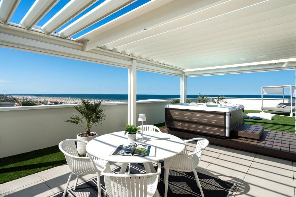 une terrasse avec une table et des chaises ainsi qu'une baignoire. dans l'établissement Litoraneo Suite Hotel, à Rimini