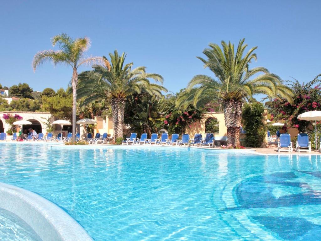 une grande piscine avec palmiers et chaises dans l'établissement Hotel I Melograni, à Vieste