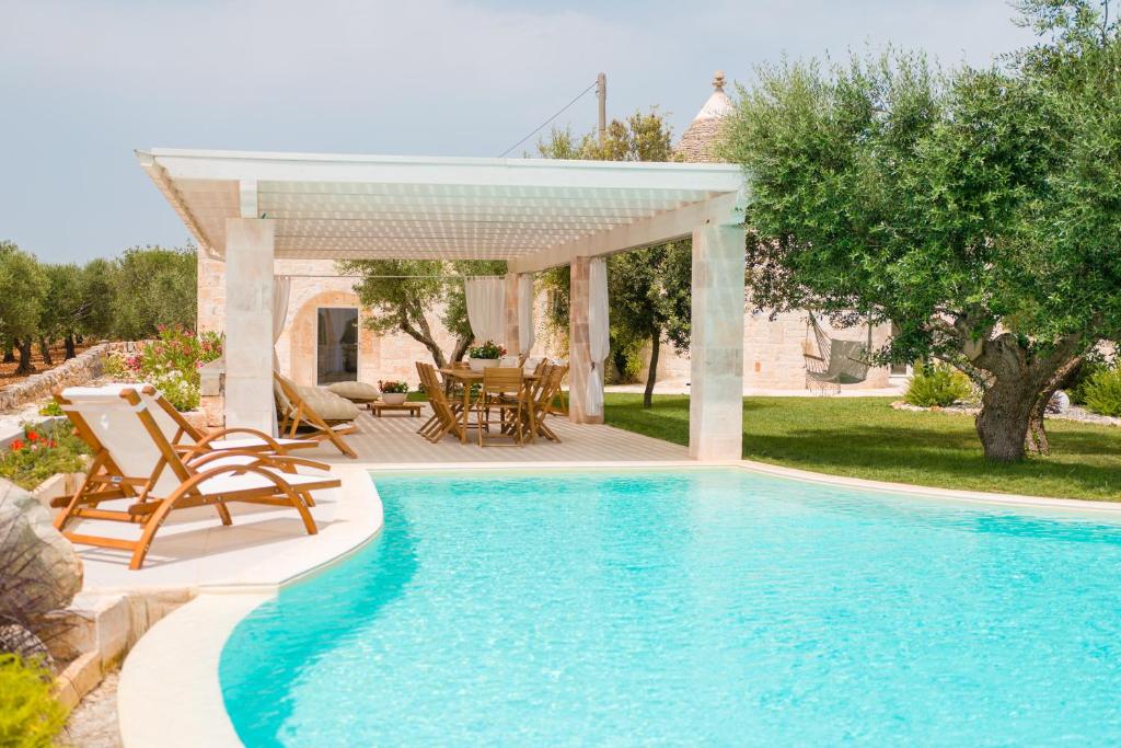 une piscine avec des chaises et une pergola à côté d'une maison dans l'établissement Trulli Petrantiqua con piscina, à Locorotondo