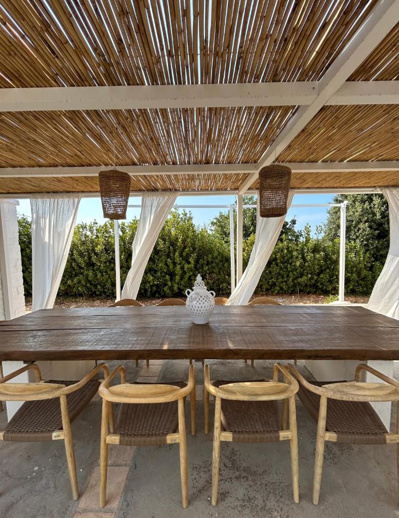 une grande table en bois avec des chaises et un plafond dans l'établissement Trulli Biancopumo - private pool, à Monopoli