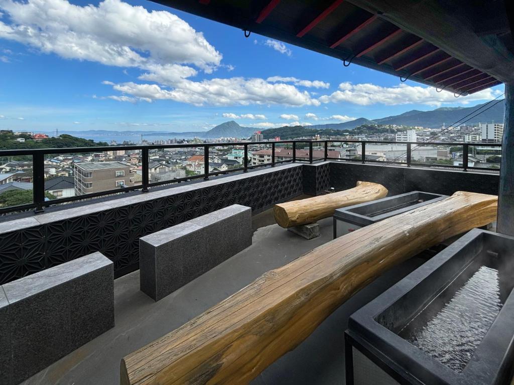 d'un balcon avec bancs et vue sur la ville. dans l'établissement 日本旅館 器 別府鉄輪 nihonryokan utsuwa beppukannnawa, à Beppu