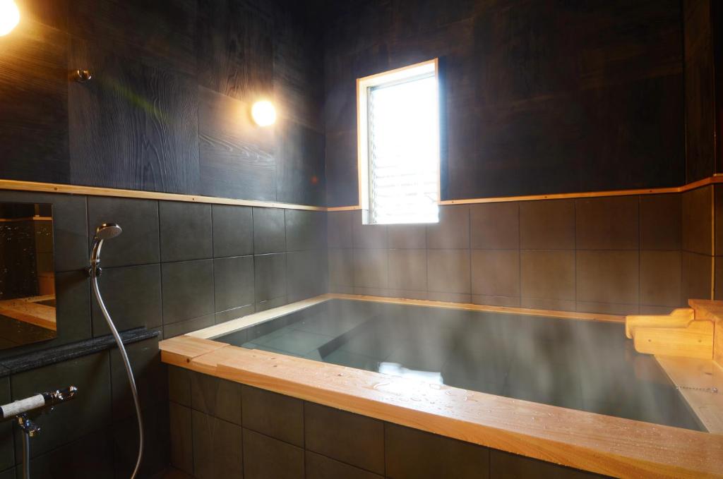 une baignoire dans une salle de bain avec une fenêtre dans l'établissement 日本旅館 器 別府鉄輪 nihonryokan utsuwa beppukannnawa, à Beppu